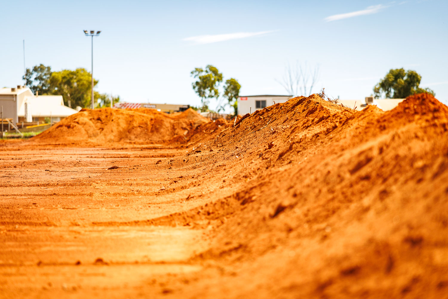Red earth mounds with tyre tracks on a cleared commercial site
